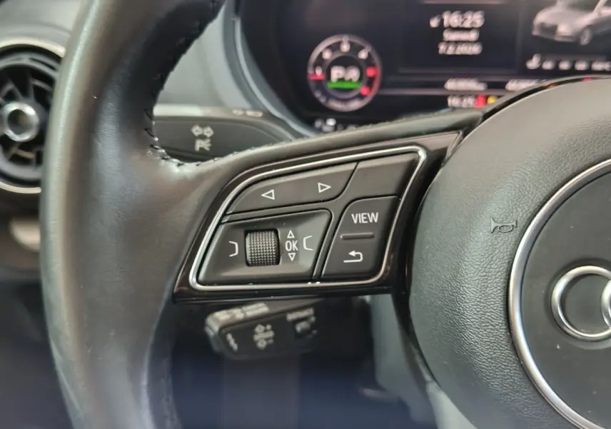 Gros plan sur le volant cuir noir de l'Audi A3 35 TDI 2020 avec commandes multifonctions côté gauche et tableau de bord numérique.