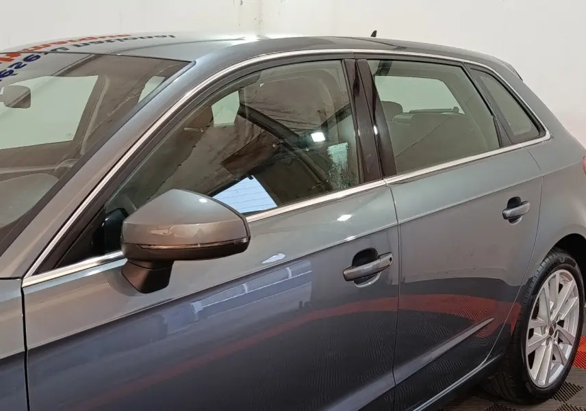 Vue côté gauche d’une Audi A3 gris foncé 2020, mettant en valeur la portière et le rétroviseur électrique.