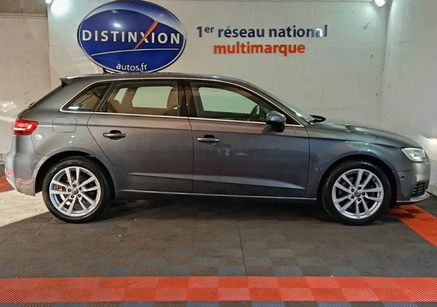 Profil côté droit d'une Audi A3 gris foncé 2020, avec jantes alliage et feux arrière LED visibles, en intérieur showroom.
