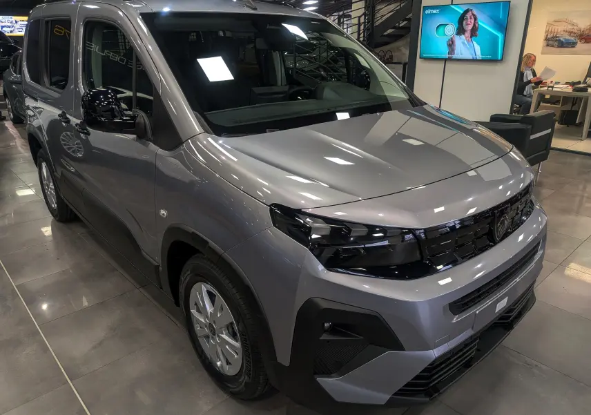 Peugeot Rifter gris acier en 3/4 avant droit, avec calandre noire et phares modernes, présenté en showroom.