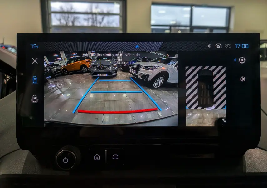 Écran de caméra de recul du Peugeot Rifter gris acier 2025, vue arrière avec guidage de trajectoire bleu et rouge.