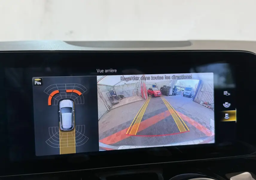 Affichage écran multimédia montrant la caméra de recul et l'aide au stationnement du Mercedes GLA 250 e gris clair.