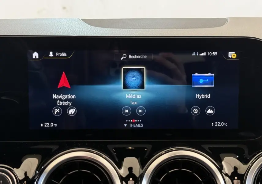 Vue rapprochée de l’écran tactile central et des aérateurs ronds chromés du tableau de bord d’une Mercedes GLA 250 e AMG Line gris clair.