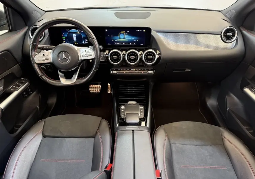 Vue intérieure avant de la Mercedes GLA 250 e AMG Line 2023, tableau de bord noir avec écran tactile et volant cuir.