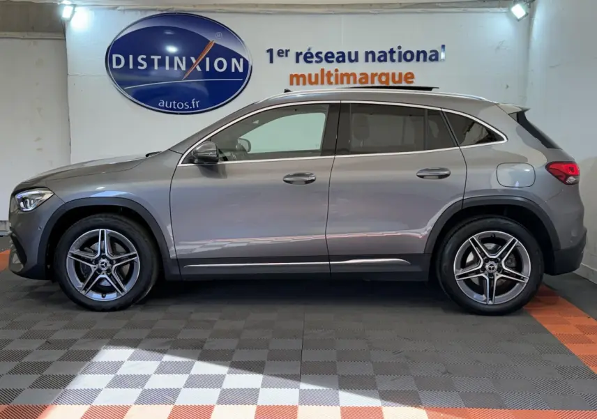 Vue de profil côté gauche d'un Mercedes GLA 250 e AMG Line gris clair hybride rechargeable dans un showroom.