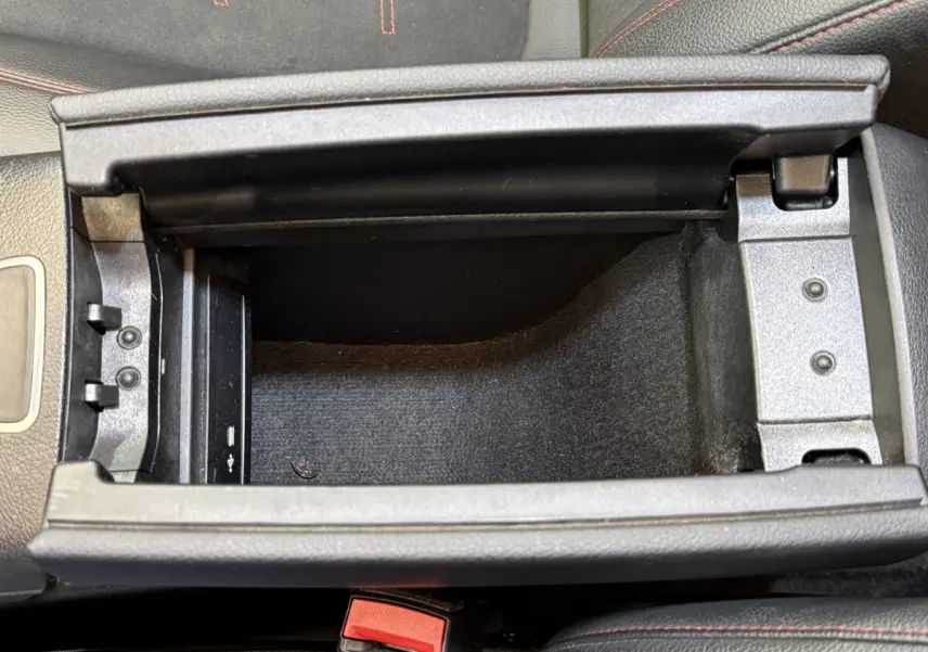 Vue plongeante sur le compartiment de rangement central noir avec surpiqûres rouges dans le Mercedes GLA 250 e AMG Line 2023.