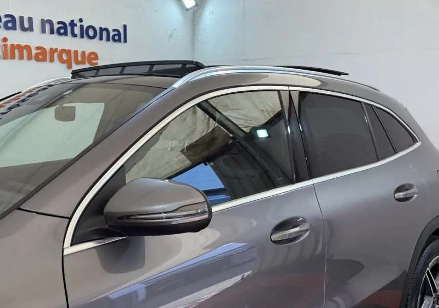 Vue latérale gauche d'un Mercedes GLA 250 e AMG Line gris clair avec rétroviseur et vitres teintées.