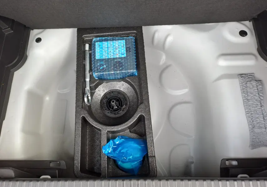 Coffre ouvert du Citroën C3 Aircross blanc banquise, vue plongeante sur le rangement d’outils sous le plancher.