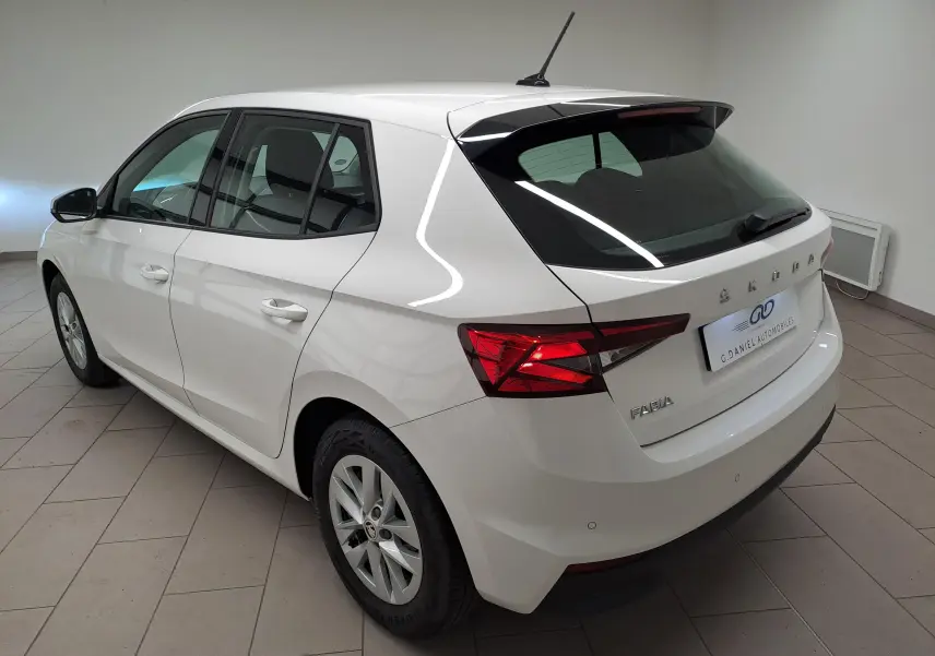 Vue 3/4 arrière droite d'une Skoda Fabia blanche Candy 2023 avec feux arrière LED et jantes alliage en intérieur showroom.