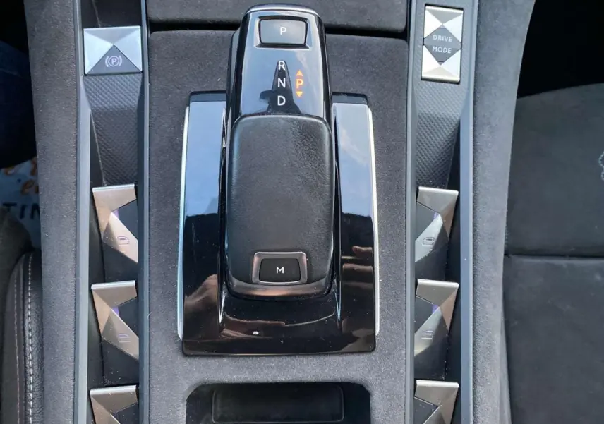 Vue rapprochée de la console centrale noire du DS7 Crossback gris foncé, avec levier de vitesses automatique et boutons triangulaires.