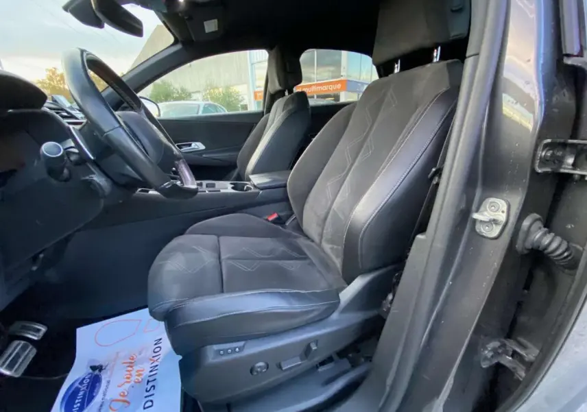 Vue intérieure côté conducteur du DS7 Crossback gris foncé, mettant en valeur les sièges en cuir avec surpiqûres décoratives.