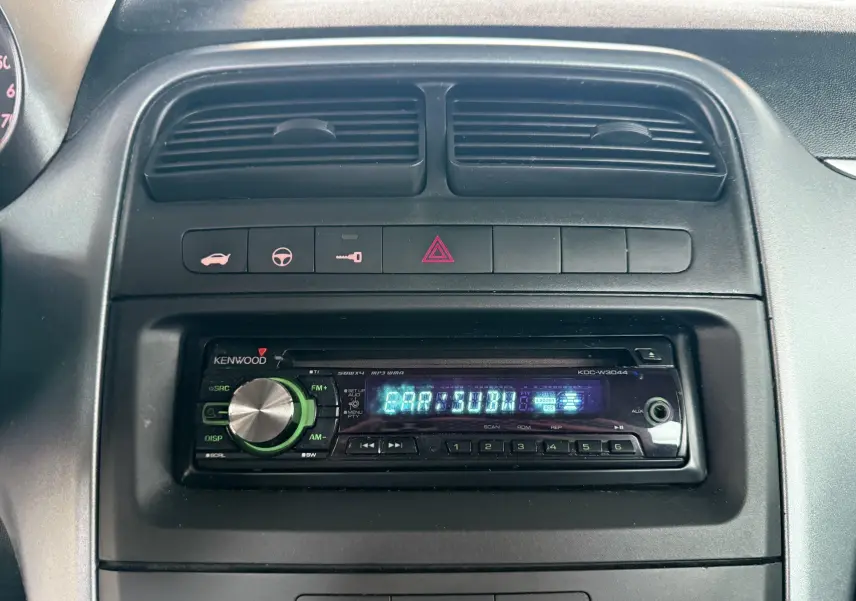 Vue rapprochée de la radio Kenwood intégrée au tableau de bord noir d'une Fiat Punto 1.2 i 65 de 2009.
