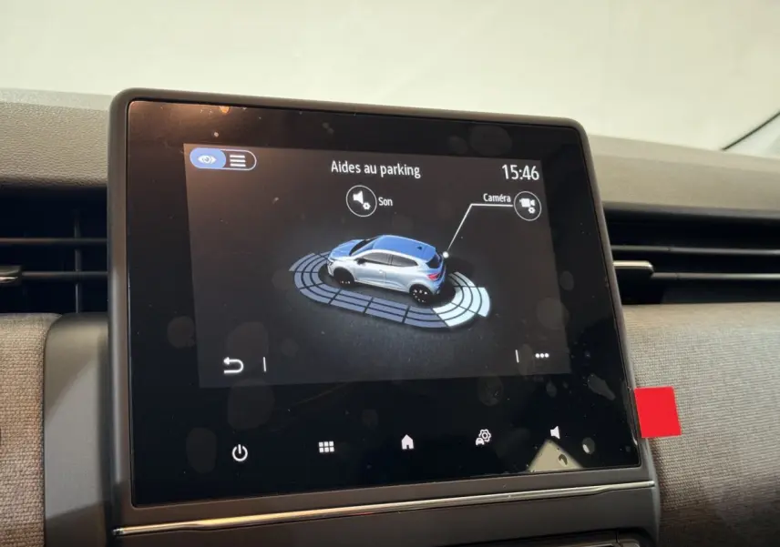 Écran tactile central montrant l'aide au stationnement d'une Renault Clio gris clair, vue intérieure rapprochée.