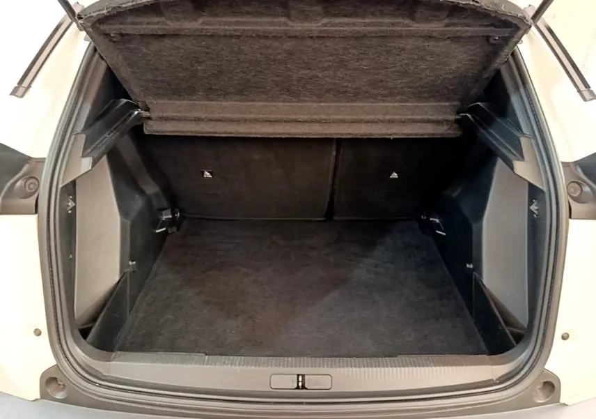 Coffre ouvert vu de l'arrière d'un Peugeot 2008 blanc, montrant l'espace de chargement vide et tapis noir.