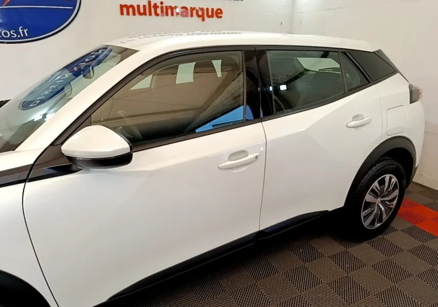 Profil côté gauche d’un Peugeot 2008 blanc, mettant en valeur les lignes anguleuses et les rétroviseurs blancs.