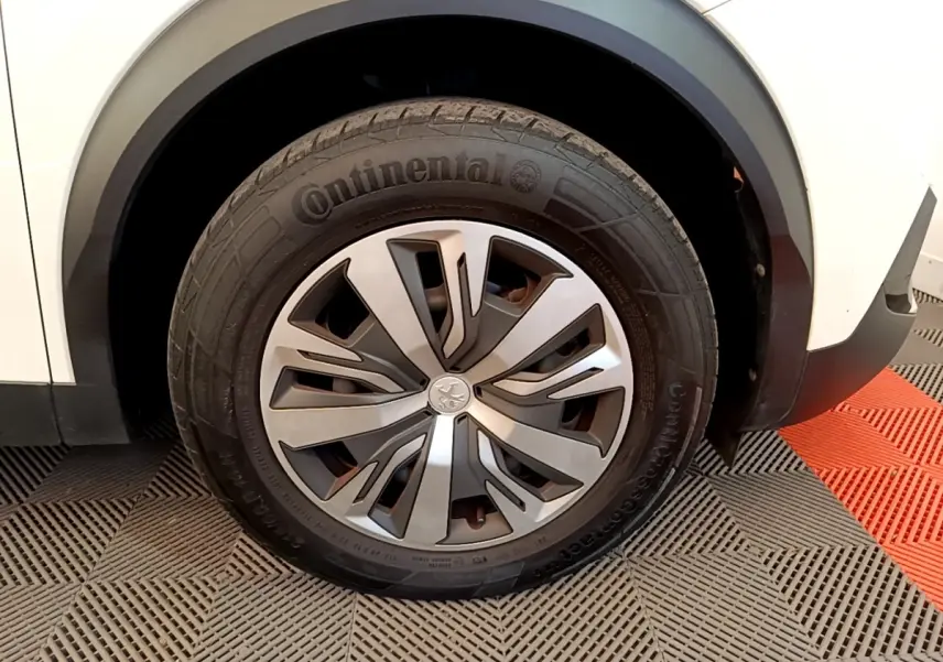 Gros plan sur la roue avant droite d’un Peugeot 2008 blanc, avec jante alliage et pneu Continental visible.