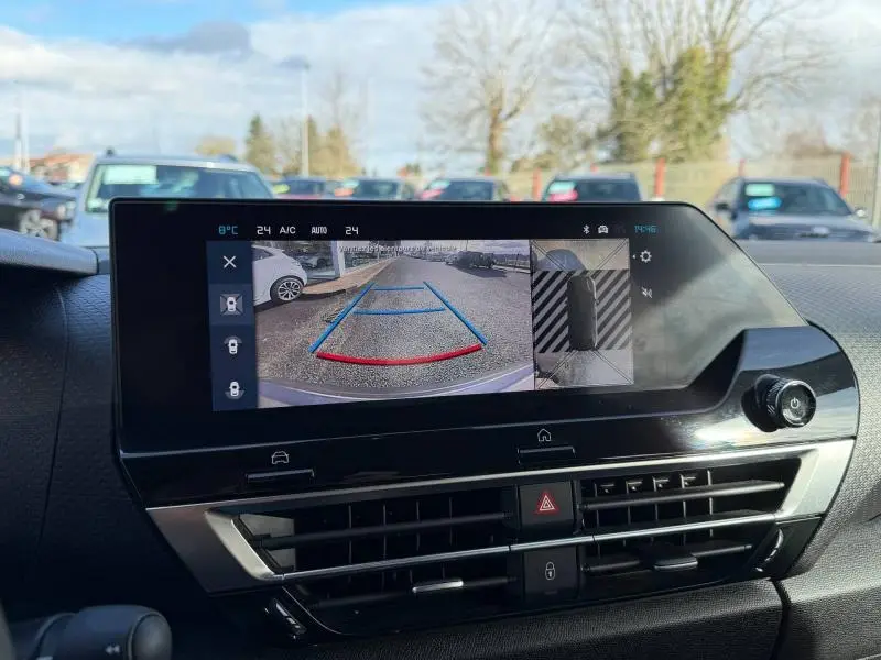 Vue intérieure du tableau de bord du Citroën C4 2024 gris, écran affichant la caméra de recul avec guidage coloré.
