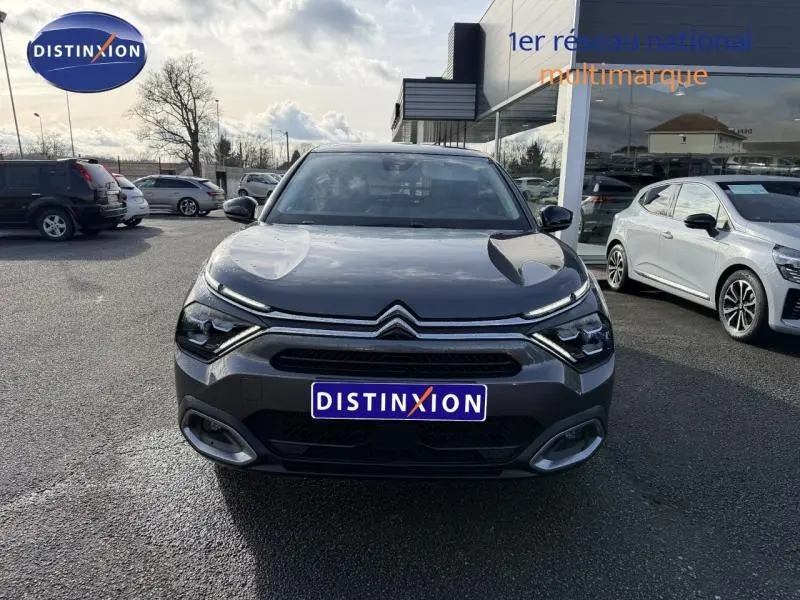 Vue avant d'une Citroën C4 gris 2024 avec calandre distinctive et phares LED, stationnée devant un showroom.