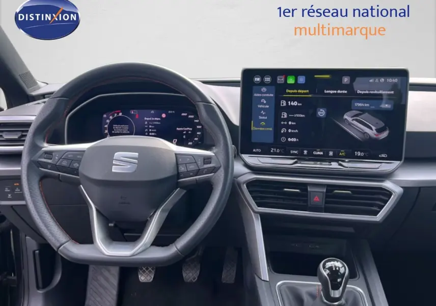 Vue intérieure centrée sur le volant et la console centrale d'une SEAT LEON ST gris magnétique, avec écran tactile et boîte manuelle.