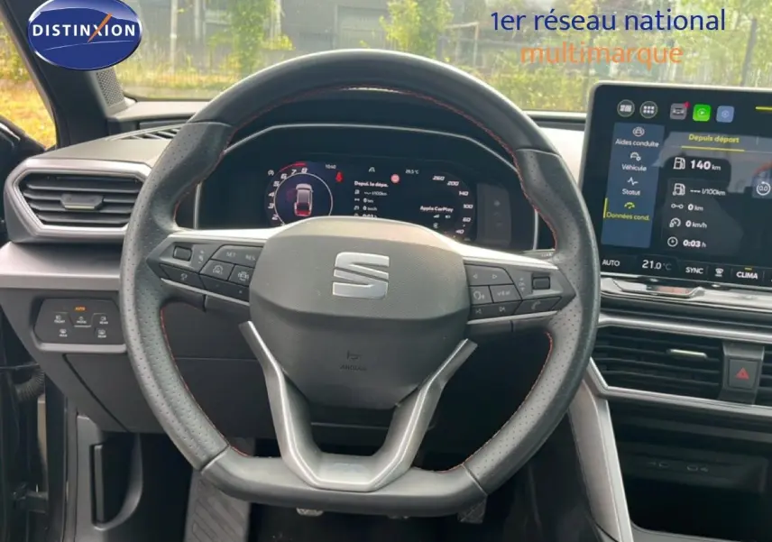 Vue intérieure centrée sur le volant perforé et les écrans numériques du tableau de bord d’une SEAT Leon ST 2025.