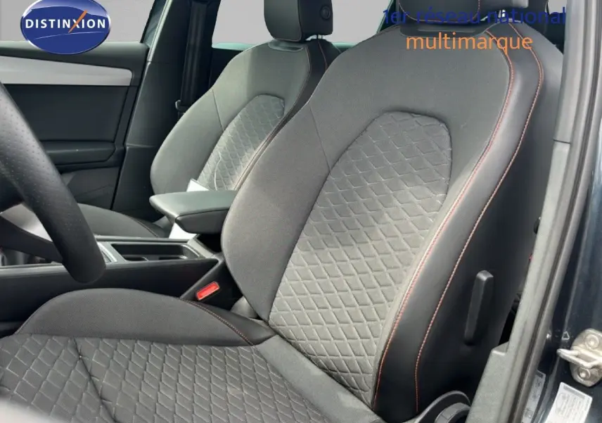 Gros plan sur les sièges avant gris noir avec surpiqûres orange du SEAT LEON ST 2025, vue côté gauche intérieur conducteur.