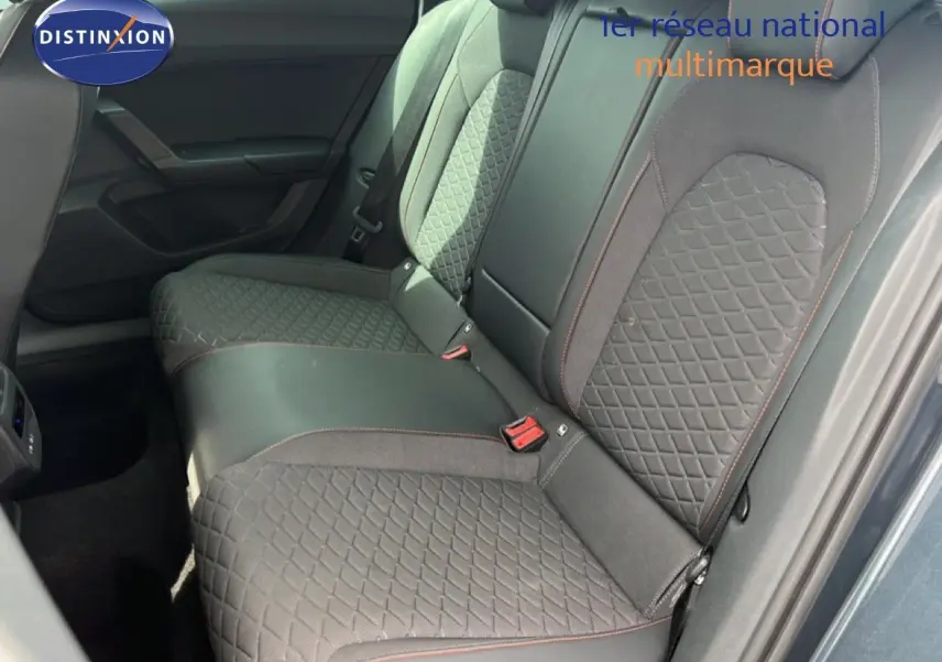 Vue intérieure des sièges arrière en tissu gris noir avec surpiqûres rouges d'une SEAT LEON ST 2025, porte ouverte côté droit.