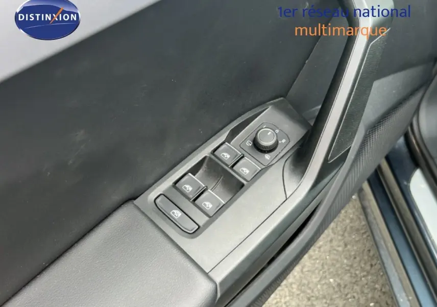 Vue rapprochée des commandes de lève-vitres et rétroviseurs sur la porte côté conducteur d’une SEAT LEON ST gris magnétique.