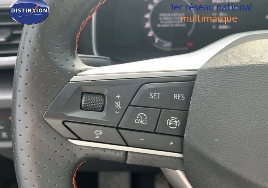 Gros plan sur les commandes au volant perforé avec surpiqûres rouges du SEAT LEON ST gris métallique 2025.