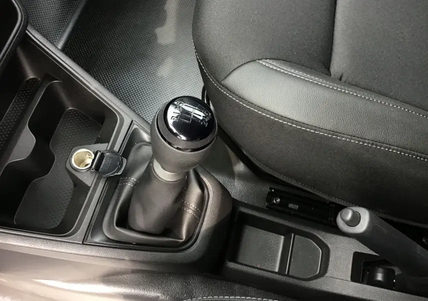 Gros plan intérieur sur le levier de vitesse manuel et la console centrale du Renault Express Van blanc, siège conducteur en tissu noir.