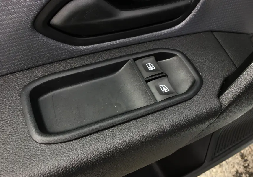 Gros plan sur les commandes électriques des vitres côté conducteur du Renault Express Van blanc 2024, intérieur noir texturé.