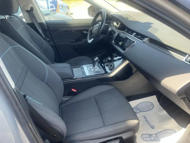Vue intérieure côté conducteur du Range Rover Evoque 2019 en Indus Silver, avec sièges noirs et tableau de bord moderne.