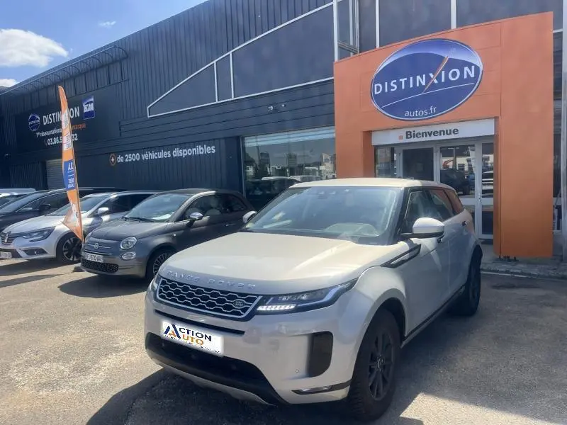 Range Rover Evoque Indus Silver vue 3/4 avant droit devant un concessionnaire Distinxion par temps ensoleillé