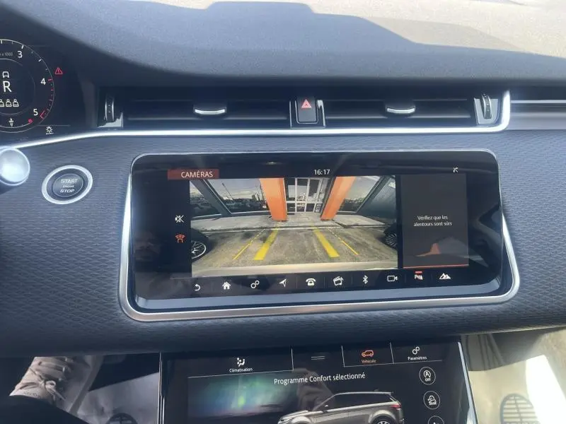 Écran tactile central du Range Rover Evoque 2019 affichant la caméra de recul avec vue sur un parking devant un bâtiment orange.