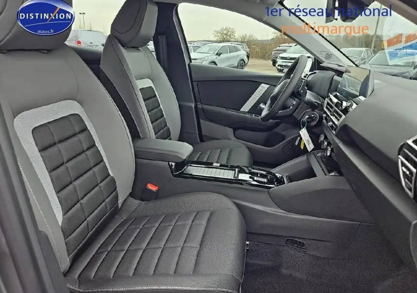 Intérieur avant droit de la Citroën C4 1.2 hybride 136 plus, sièges tissu noir et gris avec console centrale brillante.