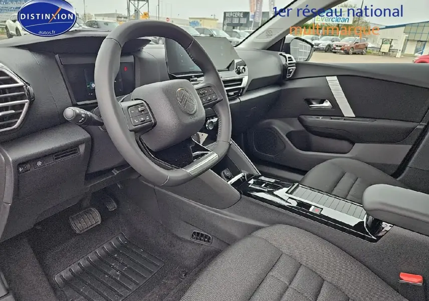 Intérieur avant droit d'une Citroën C4 gris mercury 2025 avec volant cuir et console centrale brillante noire