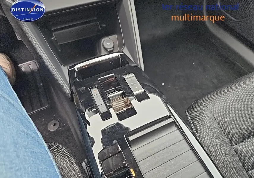 Gros plan sur la console centrale noire brillante de la Citroën C4 gris mercury, avec commandes de boîte auto et prise 12V visible.