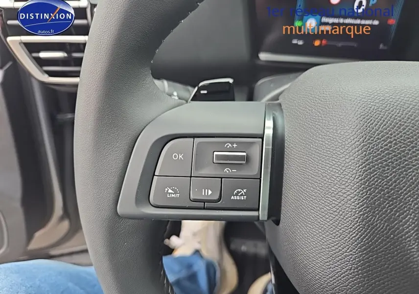 Gros plan sur les commandes gauche du volant cuir de la Citroën C4 gris mercury 2025 hybride.