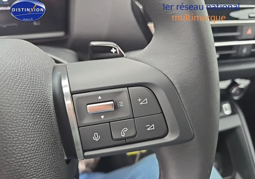 Gros plan sur les commandes au volant en cuir gris de la Citroën C4 1.2 hybride 136 plus, intérieur moderne et fonctionnel.