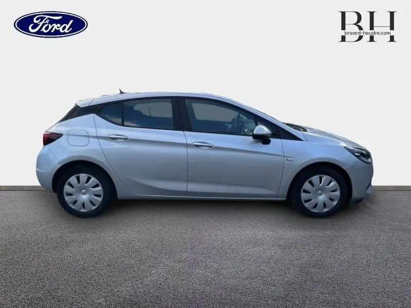 Profil côté gauche d'une Opel Astra gris minéral 2020, avec enjoliveurs et poignées ton carrosserie visibles.