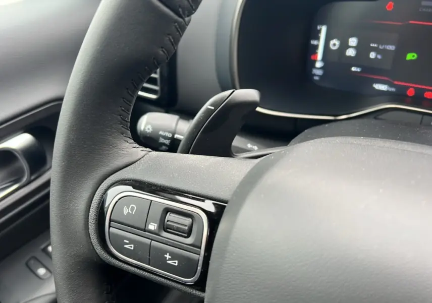 Gros plan sur le volant cuir multifonctions noir du Citroën C5 Aircross Hybrid 145, avec commandes au volant et palettes.
