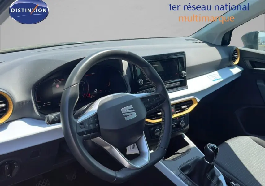 Vue intérieure du poste de conduite d'une SEAT Arona 2025 gris magnetic avec volant multifonction et levier de vitesse manuel.