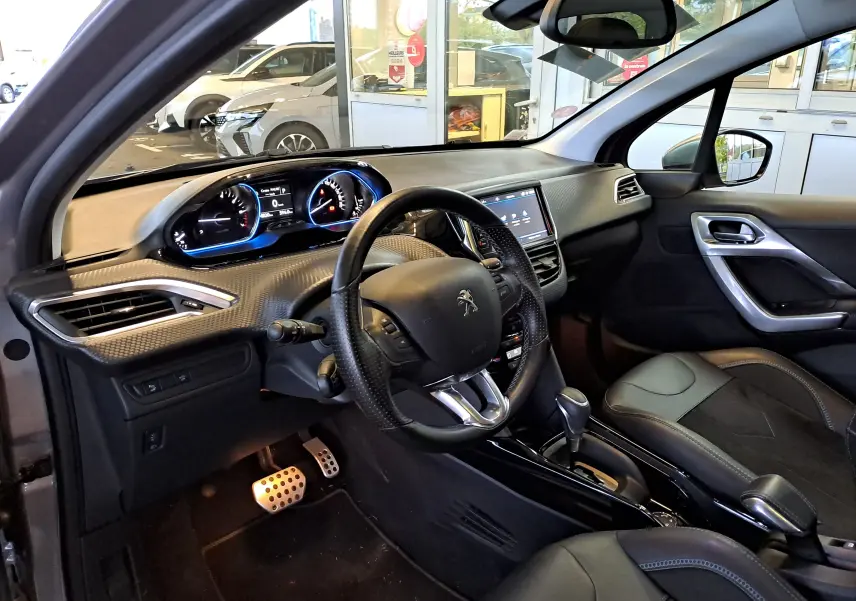 Vue intérieure côté conducteur du Peugeot 2008 gris 2019, avec tableau de bord numérique et volant compact en cuir perforé.