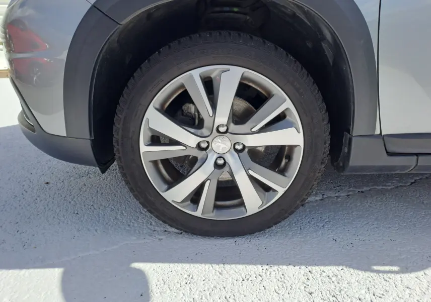Gros plan sur la roue avant gauche grise d'un Peugeot 2008 2019 avec jante alliage à cinq branches doubles.