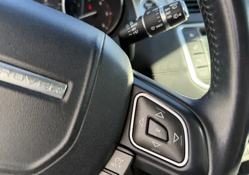 Gros plan sur le volant noir du Range Rover Evoque 2017, avec commandes multifonctions et levier d'essuie-glace visible.