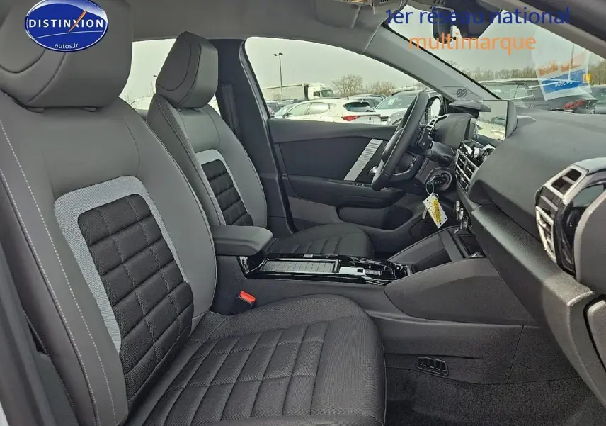 Intérieur de la Citroën C4 hybride 2025 vu côté droit, sièges tissu noir et gris avec console centrale moderne.