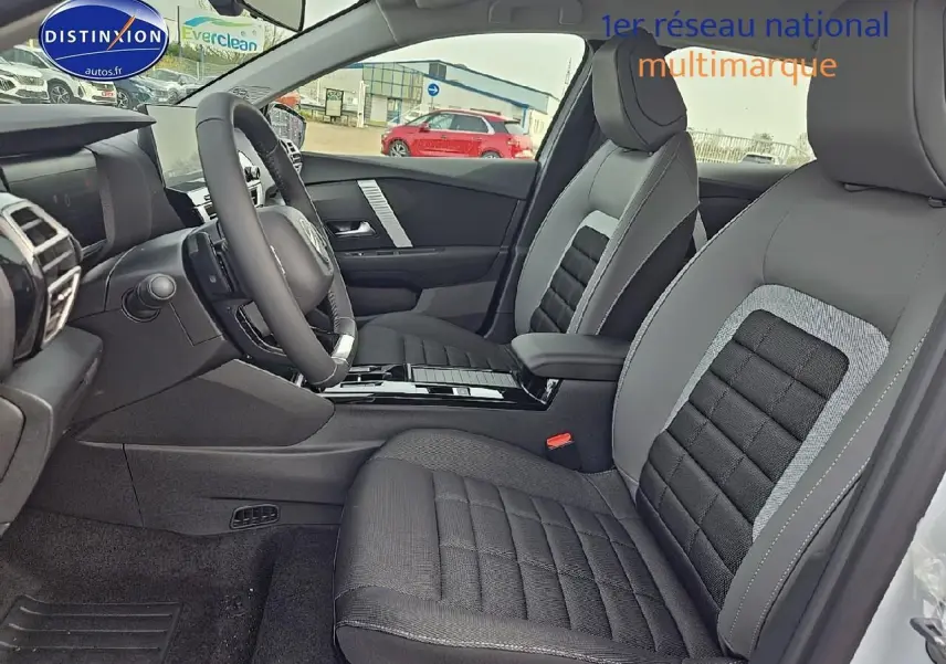 Intérieur avant droit de la Citroën C4 1.2 hybride blanc okenite avec sièges tissu noir et gris et volant cuir.