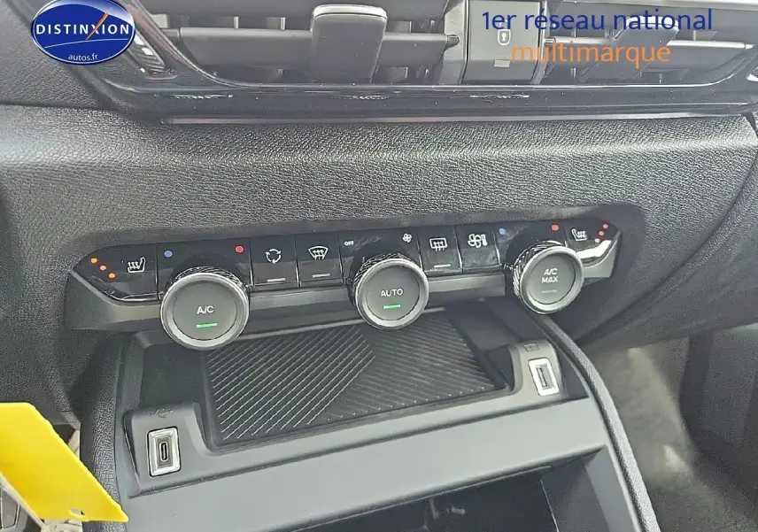 Gros plan sur la console centrale de la Citroën C4 blanche, montrant les commandes de climatisation et deux prises USB.