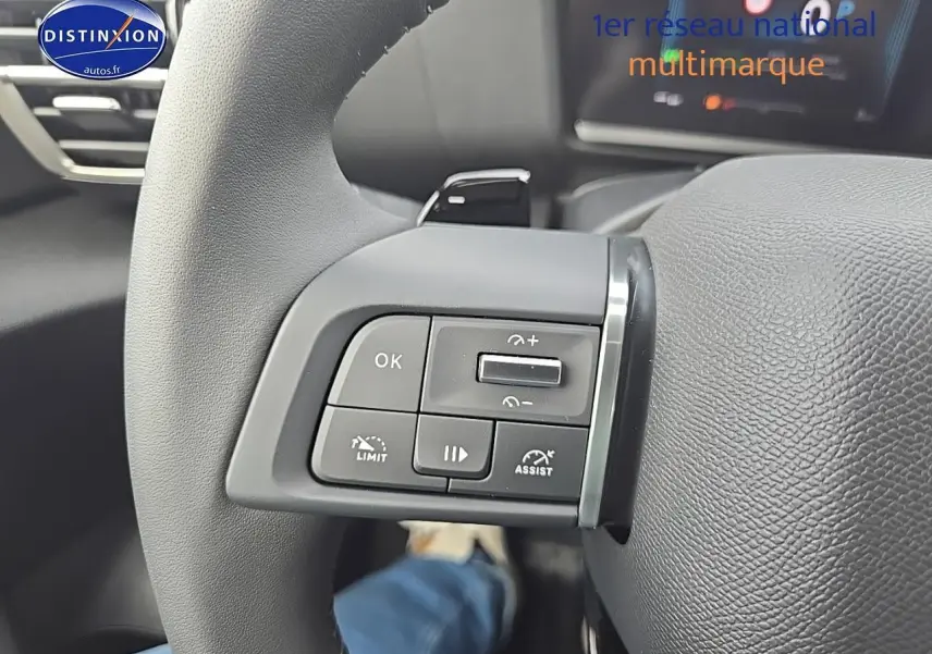 Gros plan sur les commandes au volant gauche du Citroën C4 blanc okenite, avec palettes de changement de vitesse visibles.