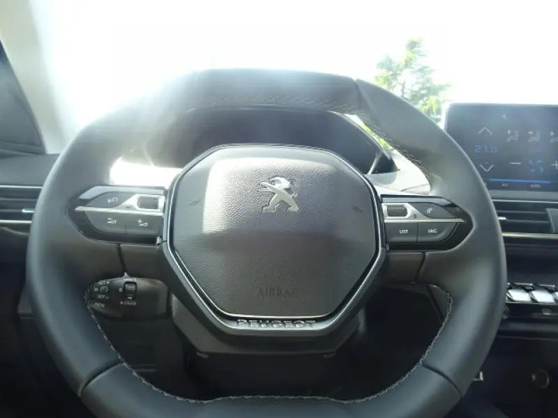 Gros plan sur le volant cuir du Peugeot 3008 gris clair 2019 avec commandes intégrées et tableau de bord numérique.