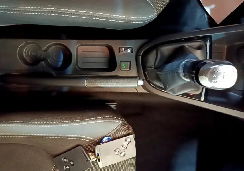 Vue intérieure centrée sur la console centrale noire de la Renault Clio Zen Energy dCi 75 avec levier de vitesse manuel et clé smart card.